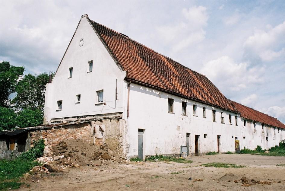 Zespół pałacowy z folwarkiem i parkiem: 2. Oficyna mieszkalna nr 3a, 2 poł. XIX, pocz. XX, 1951, w elewacji wsch. wmurowana tablica inskrypcyjna z 1591, przeniesiona z dworu.