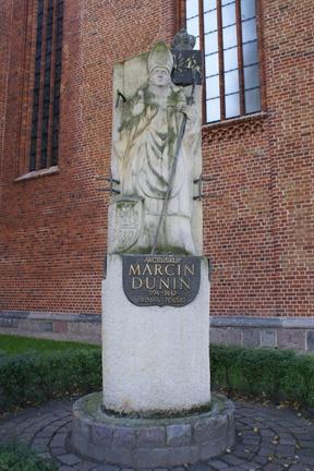 Z boków figury wystają kraty nawiązujące do więzienia Marcina Dunina w kołobrzeskiej twierdzy, w której był internowany od października 1839 do 5 sierpnia 1840 r.