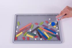 KLOCKI W OKIENKU W płaskiej, przezroczystej kasetce został umieszczony na stałe komplet kolorowych, magnetycznych klocków. Wszystkie klocki mają jednakową szerokość i różne długości (od 1 do 10 cm).