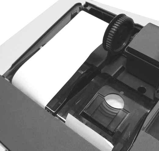zamknąć pokrywę komory mechanizmów drukujących (wprowadzając odpowiednio zaczepy pokrywy zgodnie ze zdjęciem), wyprowadzając taśmę