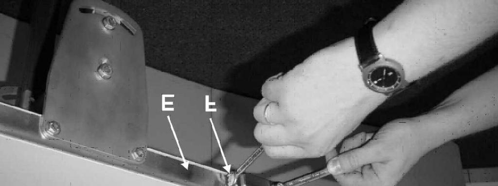 Zespół głowicy (B) można przesuwać względem ramy (E) poprzez obracanie śruby regulacyjnej (F).
