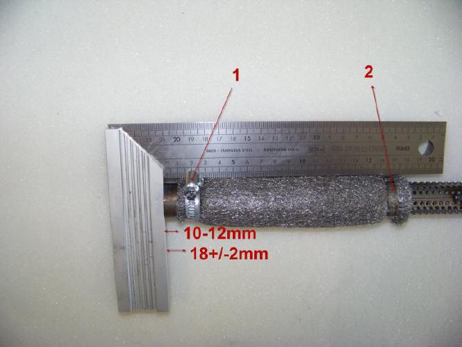 Zacisk (1) musi zostać zainstalowany w odległości 18 +/- 2mm, mierzonej od końca rury. Zacisk (2) musi zostać zamontowany na końcu stalowej maty izolacyjnej.