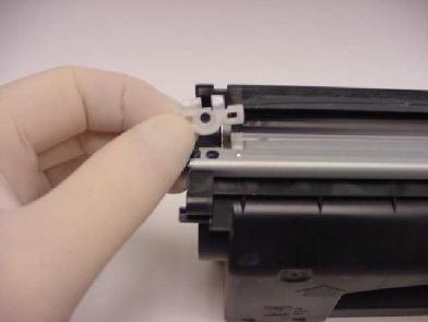 10. Zdemontuj znajdujące się po obu stronach białe plastikowe zgarniacze. Zdemontuj listwę. Wyczyść dokładnie wnętrze kasety ze starego proszku. Zasyp kasetę nowym proszkiem.