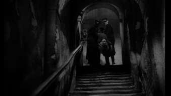 Slika 5: Mrtvo Marušo odnesejo po stopnicah Osnovna časovna linija filma Ples v dežju je linearna: začne se z večerom, ki ga Peter preživi z Magdo, nadaljuje z naslednjim dnevom (Maruša na poti v