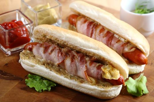 Hot dogi z grillowanymi kiełbaskami 15 minut 4 osoby Łatwe bułki do hot-dogów - 4 sztuki Sos sałatkowy koperkowo-ziołowy Knorr - 1 opakowanie kiełbaski - 4 sztuki boczek - 4 plastry ser żółty - 4