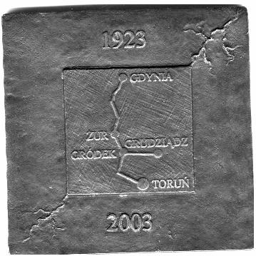 Napisy: górą - 80 LAT TRADYCJI dołem w okręgu ZE Toruń Daty roczne 1923-2003; po środku w kwadracie imitacja mapy z