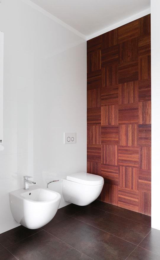 Doskonałym miejscem okazała się ściana przy WC, gdzie przyklejone zostało drewno merbau w typowym dla parkietu układzie mozaikowym.
