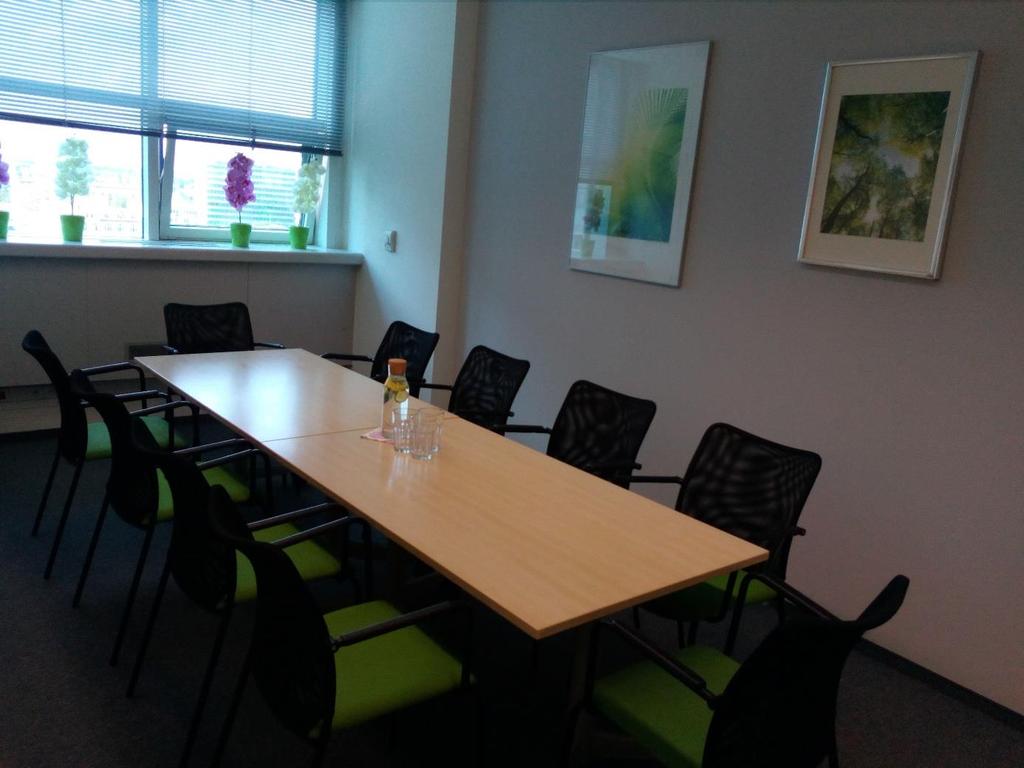 II Duża sala- nowoczesna sala przeznaczona dla spotkań do 10 osób, Zielone krzesła idealnie współgrają z jasną ścianą.