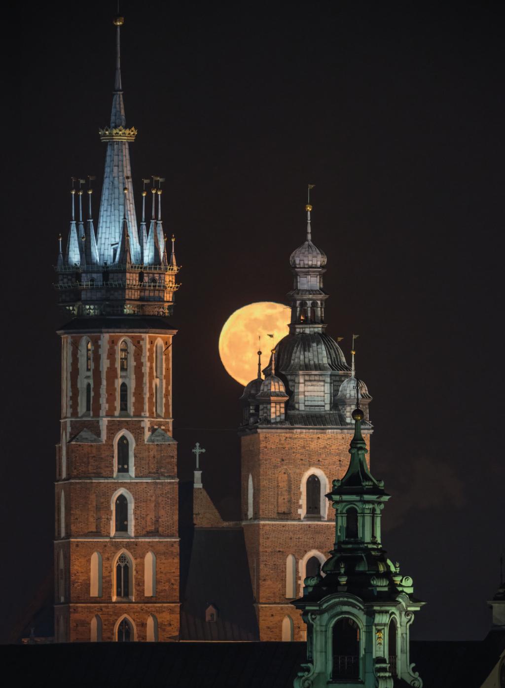 Widoczna pomiędzy wieżami kościoła Mariackiego tarcza Księżyca wschodzącego nad Krakowem. Na pierwszym planie hełm wieńczący wieżę kolegiaty św. Anny. fot.