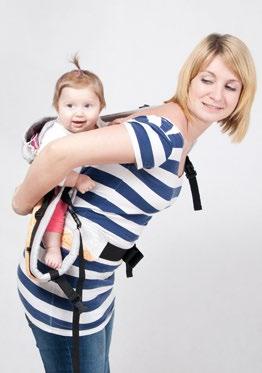 Wsuń lewą dłoń między nosidełko a swoje ciało, aby asekurować dziecko oraz pomóc sobie przy układaniu dziecka na plecach.