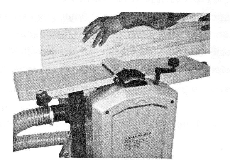 Regulacja wysokości pokrywy ochronnej odbywa się przez dźwignię po lewej stronie maszyny.