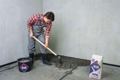 (Nakładanie zaprawy między prowadnicami, fot. Atlas) - Na całej powierzchni podłogi nakładamy zaprawę cementową.