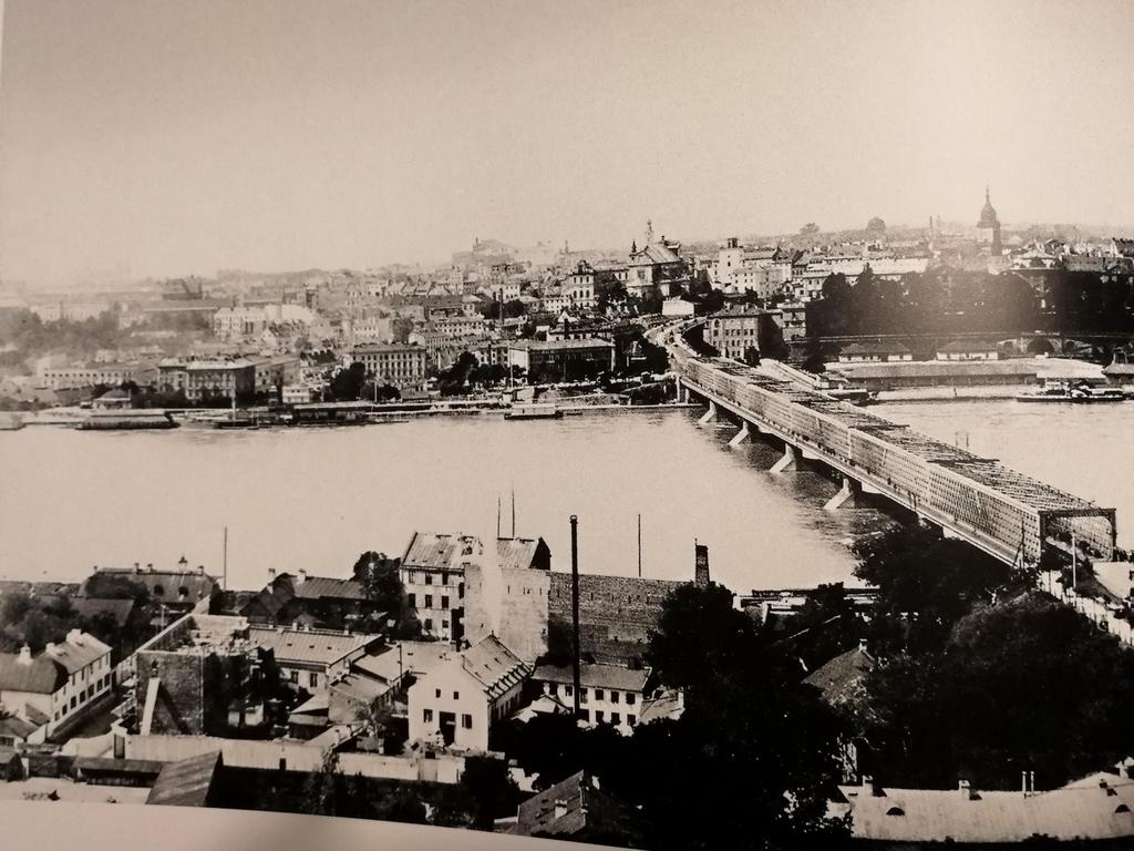 Fragment panoramy lewobrzeżnej Warszawy - widok z brzegu praskiego. Na pierwszym planie część zabudowy Pragi i most Kierbedzia.