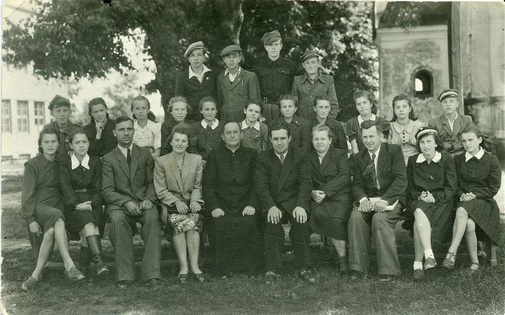 14 Zdjęcie 16 Rok 1948. Nauczyciele z uczniami klasy VII. Zdjęcie zostało zrobione na tle szkoły, kasztanów i cerkwi (później rozebranej). Budynek szkoły był wówczas bryłą prostopadłościenną.