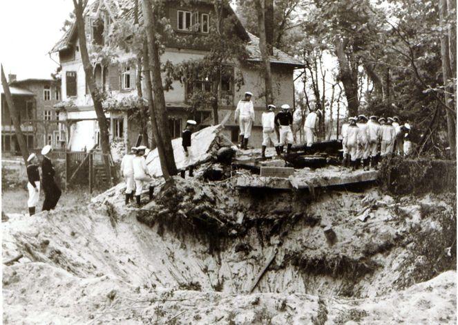 Zdjęcie ruin Warowni nr 5 i leja po bombie. Za nimi widać lekko zniszczony budynek Willi Oficerskiej, a dalej z lewej Kasyno Podoficerskie fot.