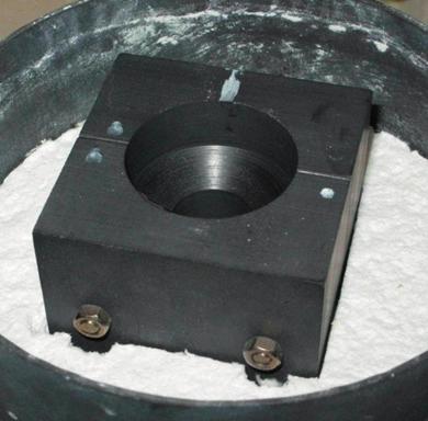 Open chamber of the Supercast Titan furnace with a graphite mold in a steel sleeve and zirconium batch placed in an insulated graphite crucible ferze próżni lub argonu.