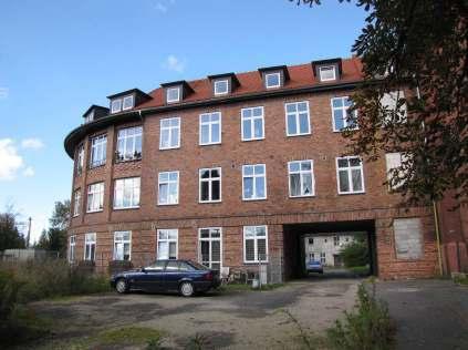 wygięte w łuk, trzykondygnacyjny, z bramą przejazdową na zaplecze budynku, dach dwuspadowy kryty dachówką karpiówką, w połaci dachowej obecne lukarny. Budynek otoczony parkiem.