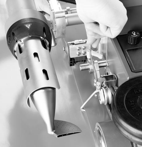 Podnieść następnie zgrzewarkę za mechanizm do podnoszenia (5) i przesunąć urządzenie na żądaną pozycję zgrzewania. Następnie odchylić rolkę prowadnicy zakładkowej (18) w dół.