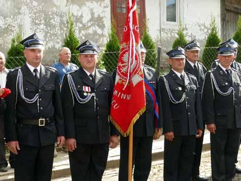 Strażacy w kolumnie marszowej na czele z pocztami sztandarowymi i orkiestrą dętą