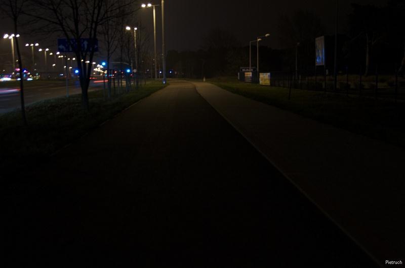 Oświetlenie w pasie dzielącym uzupełnione oświetleniem w pasie oddzielającym jezdnię od chodnika (na drugim planie). Źródło: http://rowerowytorun.com.
