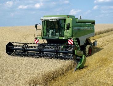 Kosiarka ta o dużej szerokości roboczej kosi rośliny i przenośnikiem poziomym układa pokos skoszonego zboża z boku maszyny.