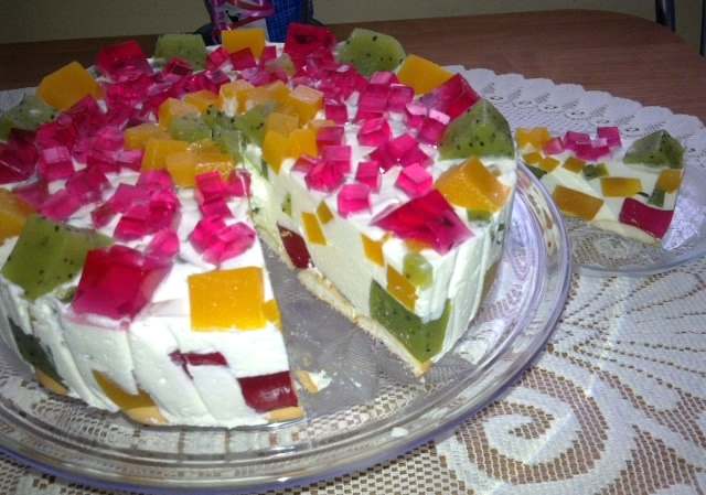 Przepis wielkanocny - Śmietanowiec z owocami Składniki: 1/2 opakowania biszkoptów 3 owoce kiwi 1 duży owoc mango 2 szklanki wody 1 galaretka czerwona 1 galaretka zielona 1 galaretka pomarańczowa 1