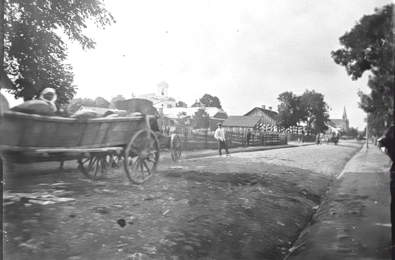 Fotografia - B Czas wykonania fotografii rok 1911. Brukowana ulica Chełmska obecnie T. Kościuszki z głębokimi rynsztokami. Chodniki wyłożone brukiem. W głebi wiatrak i kosciół rzymskokatolicki pw.św.