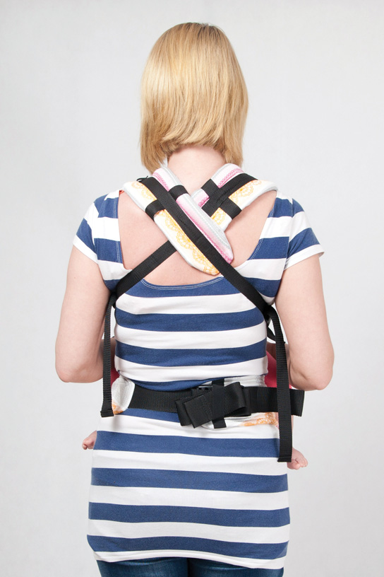 While holding your child with your right arm catch the shoulder strap on your back with your le hand and fasten it