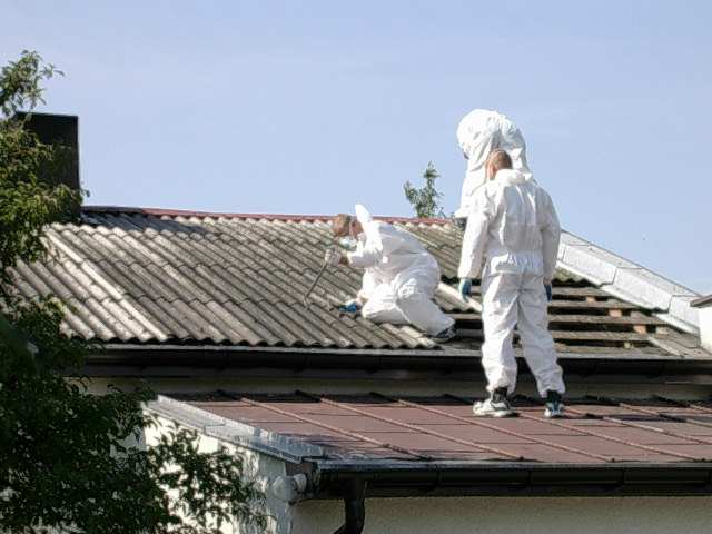 Program usuwania azbestu i wyrobów zawierających azbest Zdjęcie 8 Przykład prawidłowego postępowania przy demontażu pokrycia dachowego z eternitu, pracownik ubrany w pyłoszczelny kombinezon z maską