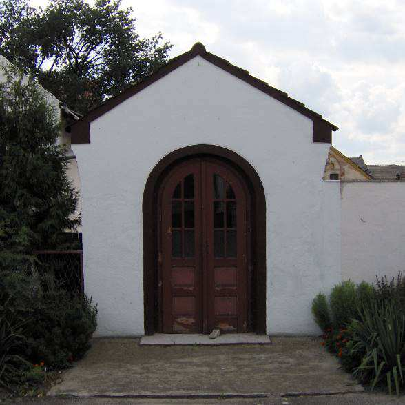 W centrum elewacji frontowej zamknięty półkoliście otwór drzwiowy. Kórnica - kapliczka przy domu ul. Szkolna 35 Zbudowana ok. poł. XIX w., przebudowana z zatarciem cech stylowych.