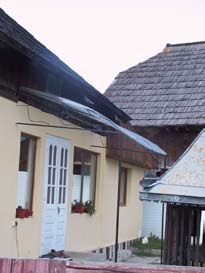 b. arhitectura casei Acoperisul asta e prea scurt, trebuie sa fie larg, ca sa curga apa repede si sa nu ajunga pe pereti. E ca suflecata. E ca o fata cu fusta mini.