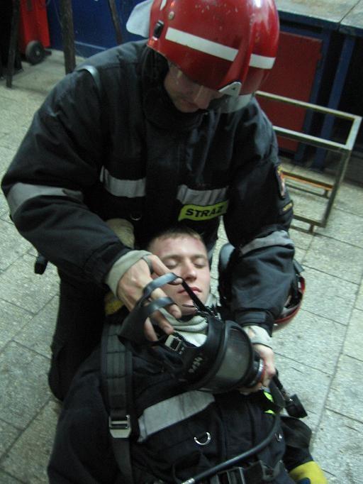6. Luzujemy paski przy masce poszkodowanego. W celu dotarcia do pasków położonych najniżej konieczne może być rozpięcie u poszkodowanego kurtki ubrania bojowego pod szyją. 7.