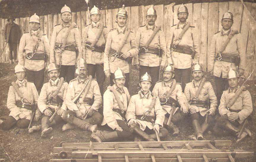 Pierwsi strażacy w Rejowcu na terenie fabryki A. Rau i Józefa Gryźińskiego. Siedzący czwarty z lewej strażak Józef Liber 5 obok sygnalisty z trąbką. Foto z 1909 roku.
