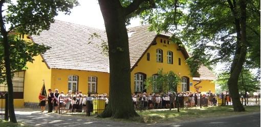 budynek Szkoły Powszechnej z 1908 roku. Początkowo budynek posiadał jedną salę lekcyjną, jednak już rok później wybudowano kolejną oraz mieszkanie dla nauczyciela. W 1926 r. działało tu 5 oddziałów.