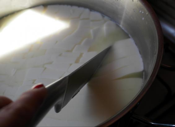 4 Po tym czasie za pomocą łyżki cedzakowej przenoś skrzep - odsączając serwatkę - do formy (może to być zwykły durszlak) wyłożonej chustą serowarską (możesz też użyć pieluchy lub gazy jak widać u