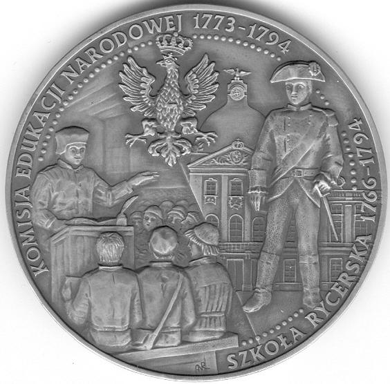21 Pod blatem ławki, na której siedzą uczniowie widoczny monogram autora, połączone litery ANR, którymi sygnują wykonywane przez siebie medale.