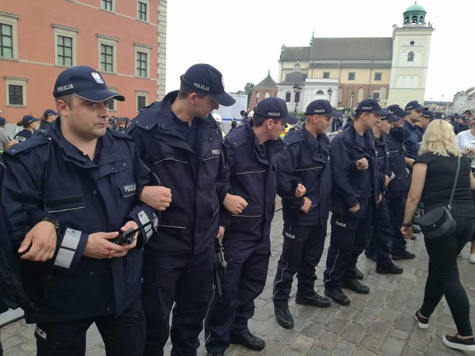 Policjanci rozstawieni wzdłuż barierek odsłaniających trasę przemarszu chwycili się pod ręce, zdjęcie z godziny 19:30 Rezerwa Policji przy Placu