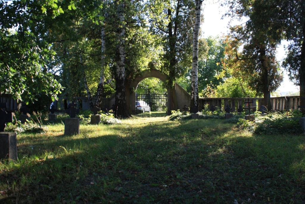 bramy wejściowej. Elementem centralnym jest drewniany krzyż łaciński z rosnącym obok dębem. Krzyże grobowe metalowe, dwuramienne, osadzone na betonowych cokołach.
