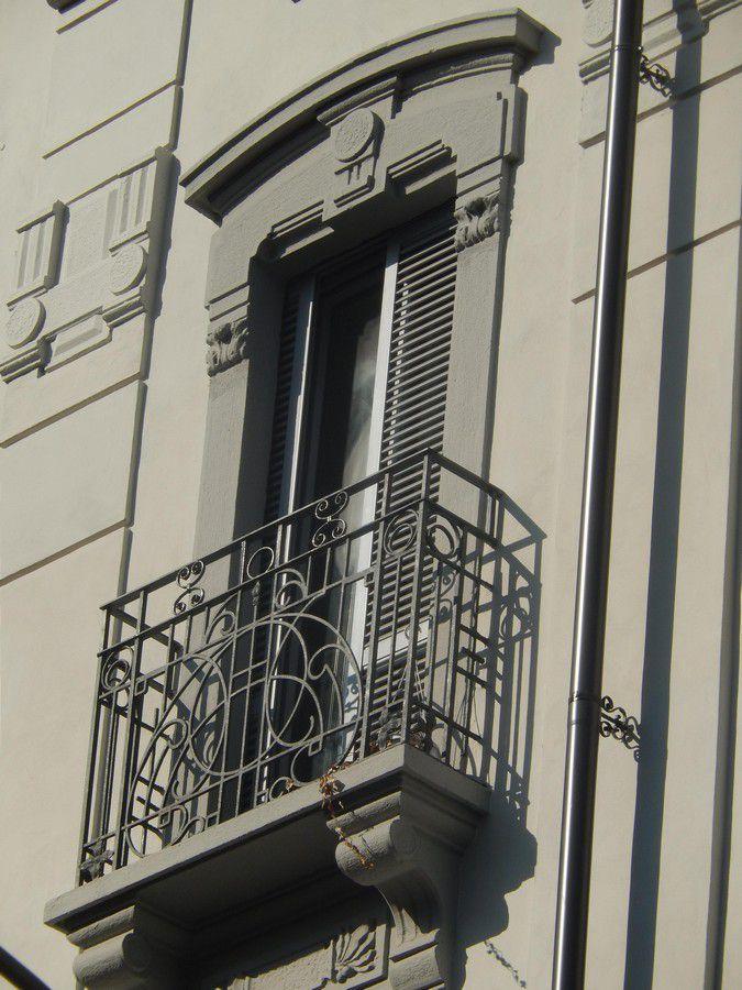 okiennice z aluminium o kolorze zimnej, jasnej szarości zostały zamontowane wewnątrz ściany starej kamienicy w centrum Mediolanu mówi