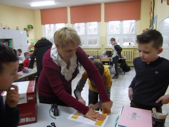 Nauczyciel i uczniowie przyklejają rysunki do sześciu ścian pudełka. 7.