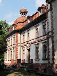 piętrowy, kryty dachem mansardowym z lukarnami. Założony na rzucie prostokąta, z bocznymi ryzalitami zakończonymi ozdobnymi szczytami.