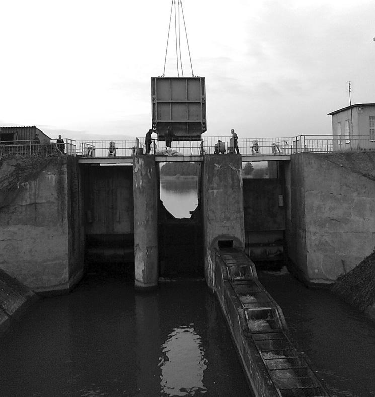 a b RYSUNEK 2. Jaz w zaporze głównego zbiornika w Zesławicach: a widok od strony dolnej wody, b wymiary zasuw (widok od strony górnej wody) FIGURE 2.