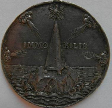Rewers wypełnia obelisk zwieńczony orłem polskim, trwający nieporuszenie IMMOBILIS /pol. bezpieczny, niewzruszony/ mimo atakujących go gwałtownie fal i wiatrów.