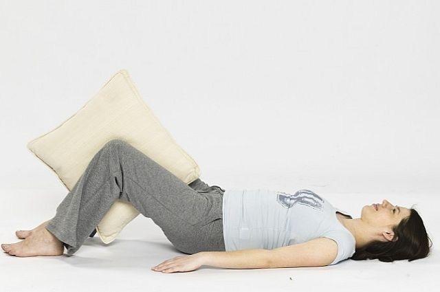Leżąc, wsuń poduszkę między nogi ugięte w kolanach. Ściśnij ją 20 razy, tak żeby napiąć mięśnie wewnętrzne ud. Powtórz 20 razy.