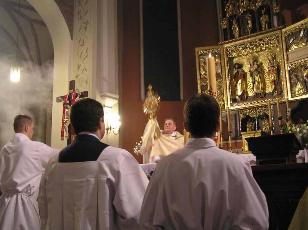 Kapłan błogosławi wiernych Najświętszym Sakramentem i chowa Go do tabernakulum.