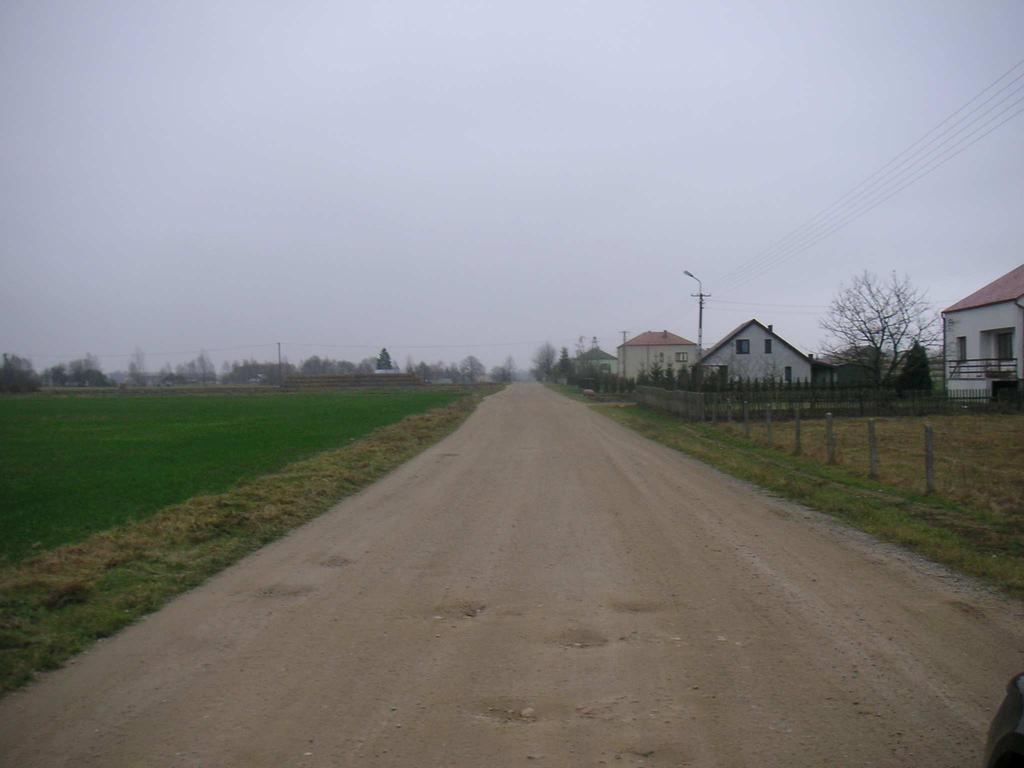 w złym stanie liczne doły i nierówności uzupełnione są kruszywem łamanym. Wzdłuż projektowanej drogi znajduje się zabudowa zagrodowa wraz z łąkami i polami uprawnymi.