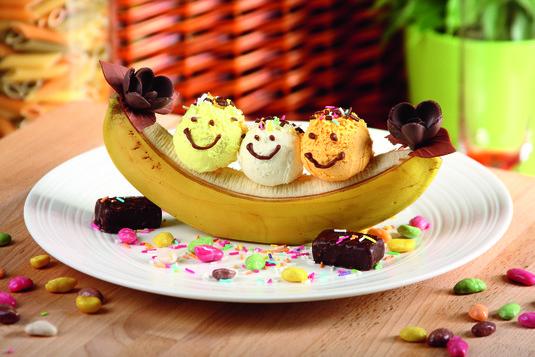 Lody z bananami "Kanu" Algida Śmietankowa Trio Tropicana banany 2 sztuki polewa czekoladowa kolorowe drażetki owocowe czekoladowe cukierki lukrowane kwiatki kolorowa posypka patyczki 15 minut 2 osoby