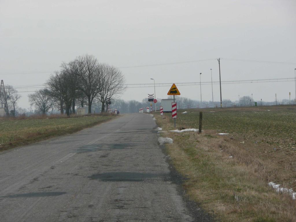 Droga o nawierzchni asfaltowej, w rejonie przejazdu brak chodników.