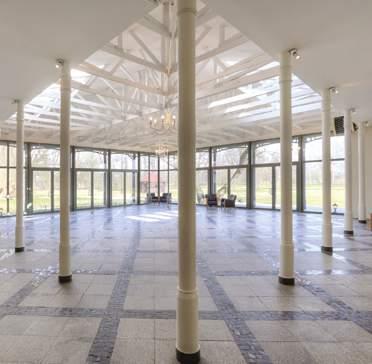 Zarówno formą urbanistyczną, tworząc wewnętrzny dziedziniec, jak i detalem architektonicznym w formie drewnianych żerdzi na elewacji, nawiązuje do zabudowy wiejskiej na Mazowszu.