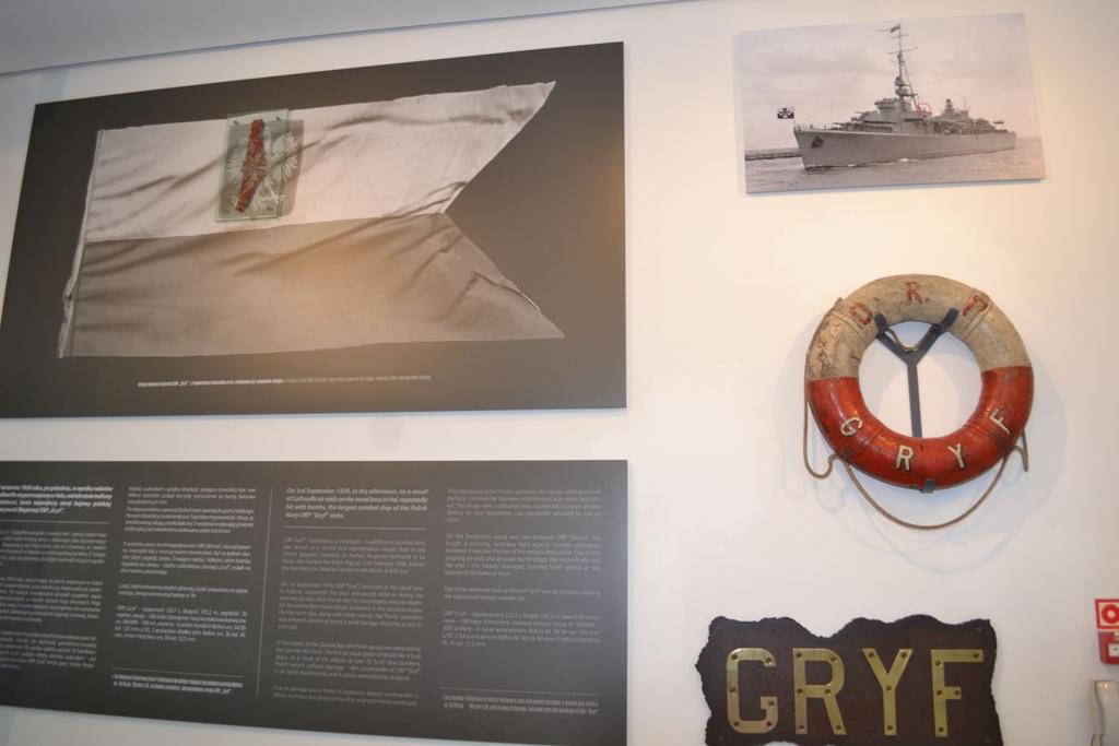 Pamiątki ze stawiacza min ORP Gryf : mosiężne litery składające się na nazwę okrętu, koło ratunkowe oraz szczątki bandery z fragmentem orła. Fot. M.